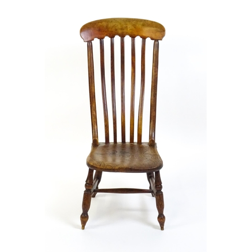 1746 - A 19thC lathe back nursing chair with a shaped elm seat raised on four turned tapering legs united b... 