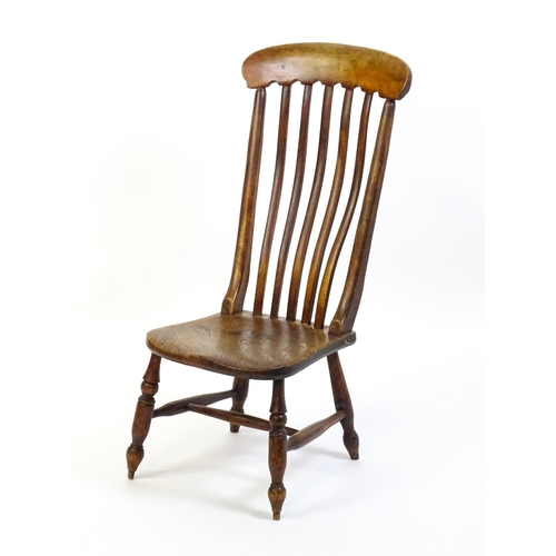 1746 - A 19thC lathe back nursing chair with a shaped elm seat raised on four turned tapering legs united b... 