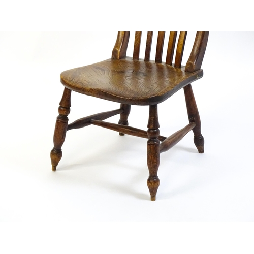 1746 - A 19thC lathe back nursing chair with a shaped elm seat raised on four turned tapering legs united b... 