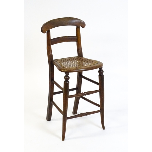 1749 - A Victorian child's chair with a bowed top and mid rail above a caned seat and raised on turned tape... 