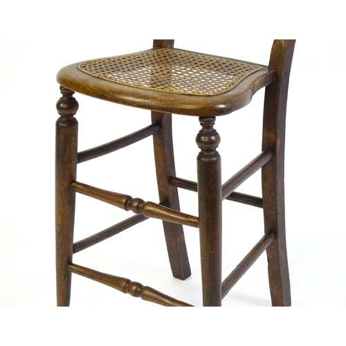 1749 - A Victorian child's chair with a bowed top and mid rail above a caned seat and raised on turned tape... 