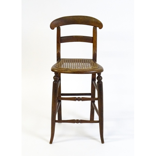 1749 - A Victorian child's chair with a bowed top and mid rail above a caned seat and raised on turned tape... 