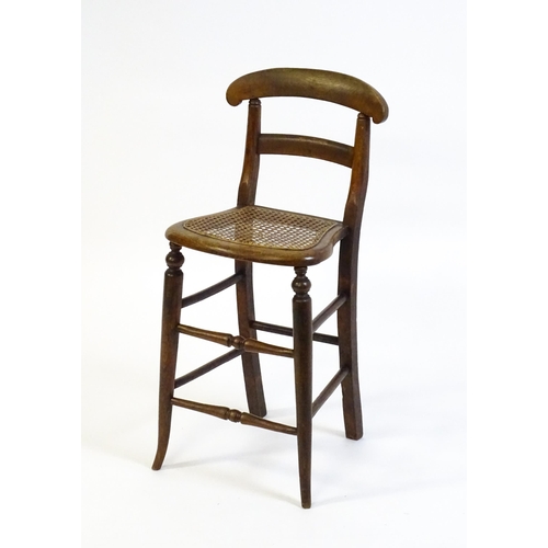 1749 - A Victorian child's chair with a bowed top and mid rail above a caned seat and raised on turned tape... 