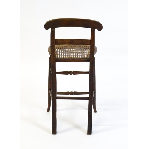 1749 - A Victorian child's chair with a bowed top and mid rail above a caned seat and raised on turned tape... 