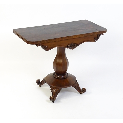 1754 - A 19thC mahogany tea table with a carved floral front panel above a canted and shaped pedestal above... 