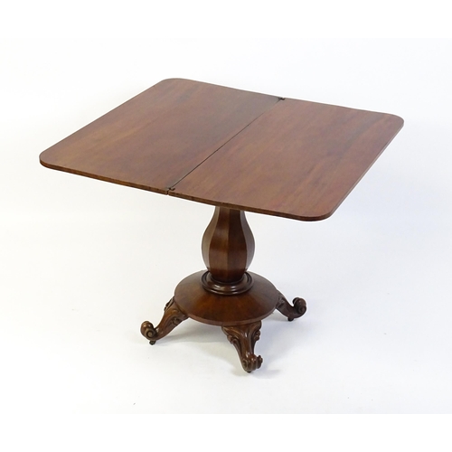 1754 - A 19thC mahogany tea table with a carved floral front panel above a canted and shaped pedestal above... 