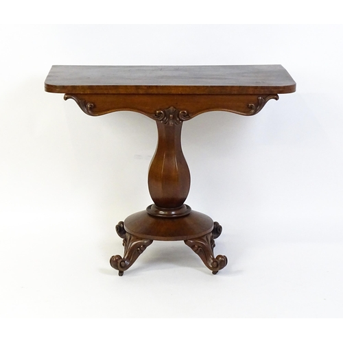 1754 - A 19thC mahogany tea table with a carved floral front panel above a canted and shaped pedestal above... 