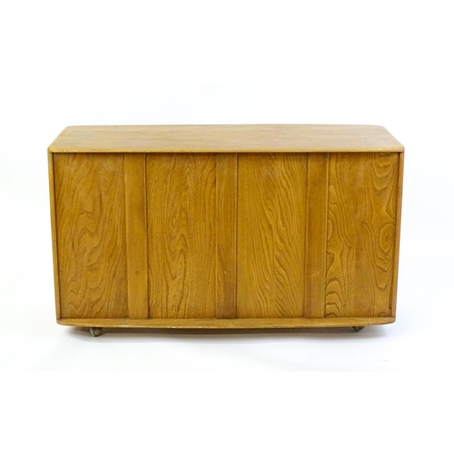 1761 - Vintage / Retro: An elm Ercol Windsor sideboard with three panelled doors above two long drawers to ... 
