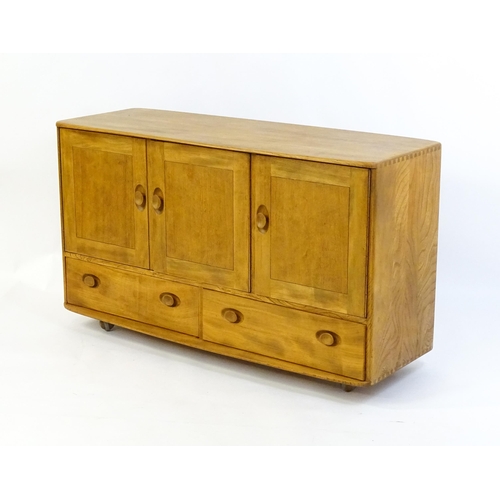 1761 - Vintage / Retro: An elm Ercol Windsor sideboard with three panelled doors above two long drawers to ... 