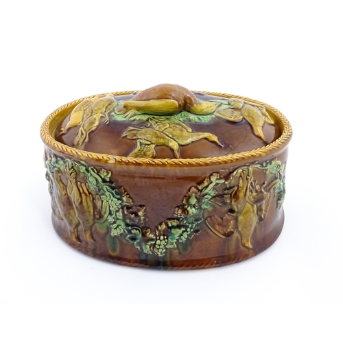 151 - A Victorian majolica game pie tureen and cover with relief decoration depicting birds, hares and flo... 