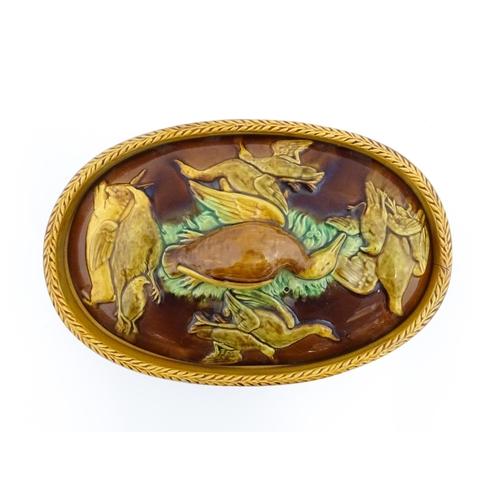 151 - A Victorian majolica game pie tureen and cover with relief decoration depicting birds, hares and flo... 