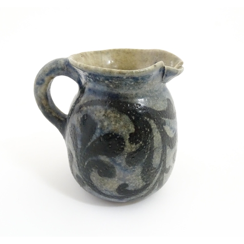 59 - A stoneware jug with blue glaze and foliate decoration. Signed under Martin Bros London. Approx. 4