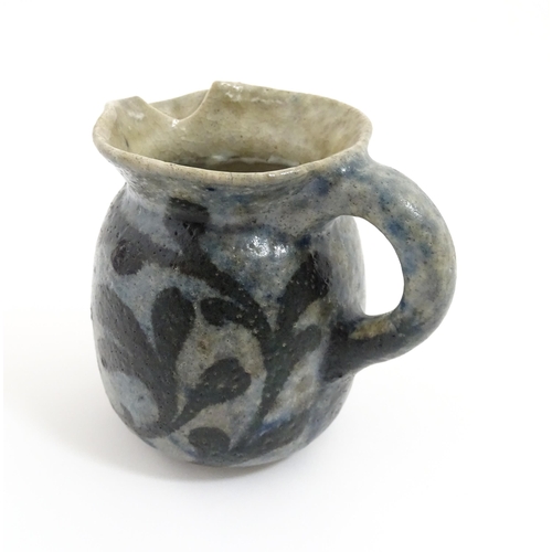 59 - A stoneware jug with blue glaze and foliate decoration. Signed under Martin Bros London. Approx. 4