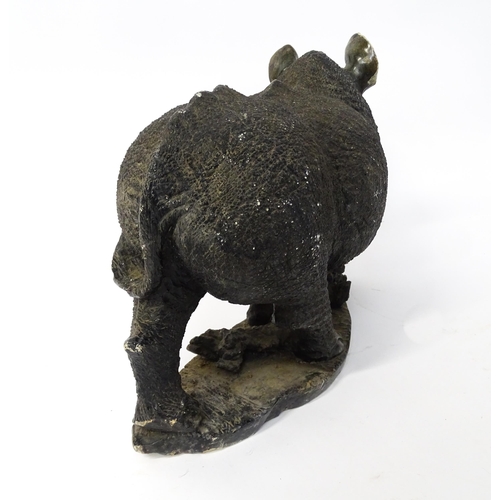 1260 - A large 20thC carved stone model of a rhinoceros / rhino on a naturalistic base. Approx. 15 1/2