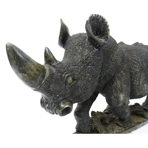 1260 - A large 20thC carved stone model of a rhinoceros / rhino on a naturalistic base. Approx. 15 1/2