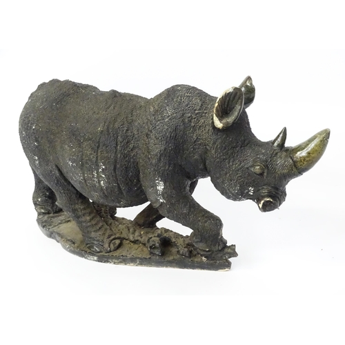 1260 - A large 20thC carved stone model of a rhinoceros / rhino on a naturalistic base. Approx. 15 1/2