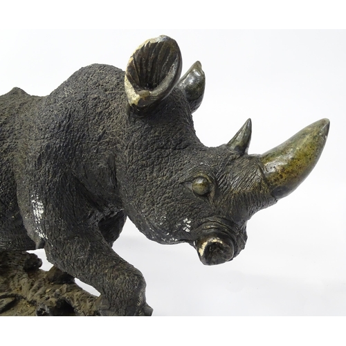 1260 - A large 20thC carved stone model of a rhinoceros / rhino on a naturalistic base. Approx. 15 1/2