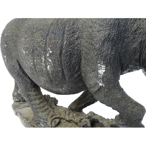 1260 - A large 20thC carved stone model of a rhinoceros / rhino on a naturalistic base. Approx. 15 1/2