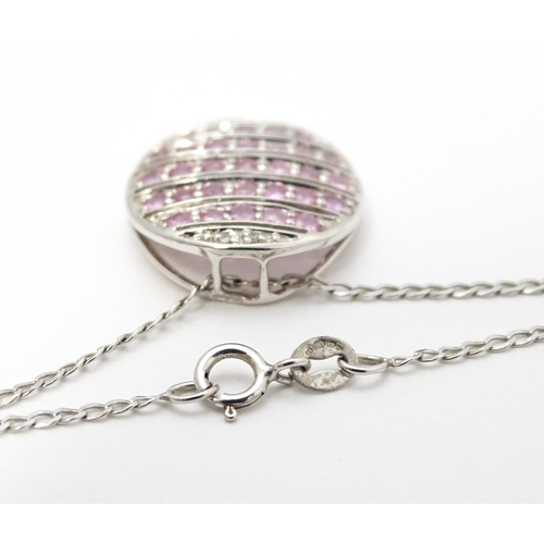 781 - A 9ct white gold pendant of oval form set with diamonds and pink sapphires. On 9ct white gold chain.... 