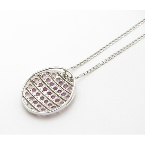 781 - A 9ct white gold pendant of oval form set with diamonds and pink sapphires. On 9ct white gold chain.... 