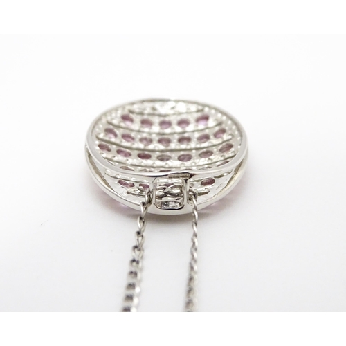 781 - A 9ct white gold pendant of oval form set with diamonds and pink sapphires. On 9ct white gold chain.... 