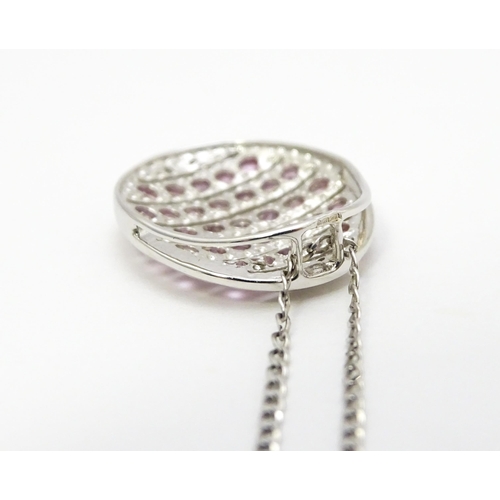 781 - A 9ct white gold pendant of oval form set with diamonds and pink sapphires. On 9ct white gold chain.... 