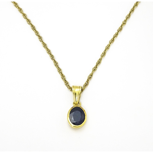 787 - A yellow metal pendant set with central sapphire on a 9ct gold chain. Pendant approx. 1 3/4