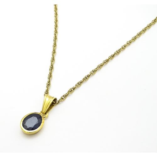 787 - A yellow metal pendant set with central sapphire on a 9ct gold chain. Pendant approx. 1 3/4