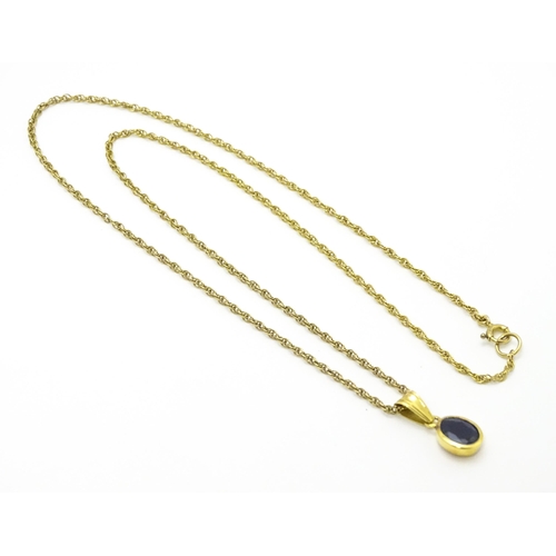 787 - A yellow metal pendant set with central sapphire on a 9ct gold chain. Pendant approx. 1 3/4