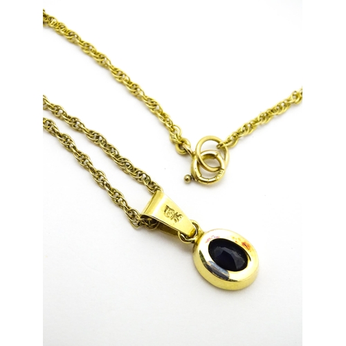 787 - A yellow metal pendant set with central sapphire on a 9ct gold chain. Pendant approx. 1 3/4