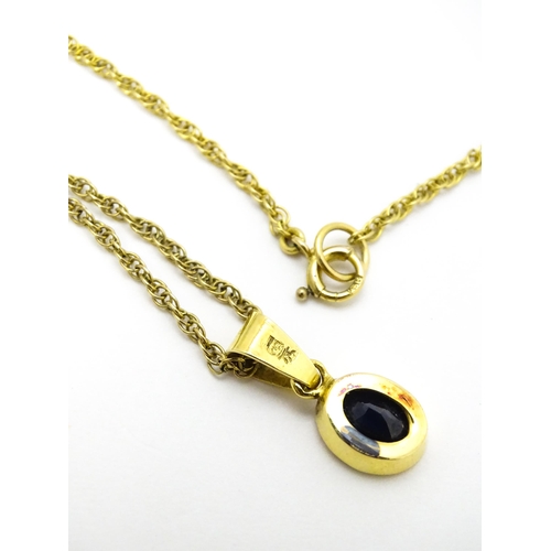 787 - A yellow metal pendant set with central sapphire on a 9ct gold chain. Pendant approx. 1 3/4