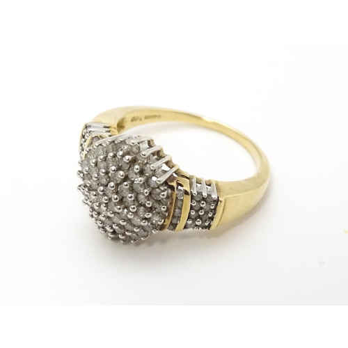 798 - A 9ct gold cocktail ring set with a central cluster of diamonds flanked by further diamonds to shoul... 