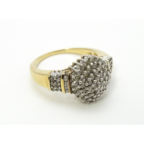 798 - A 9ct gold cocktail ring set with a central cluster of diamonds flanked by further diamonds to shoul... 