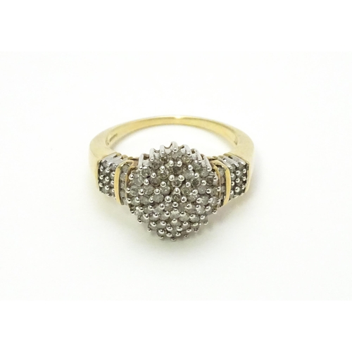 798 - A 9ct gold cocktail ring set with a central cluster of diamonds flanked by further diamonds to shoul... 