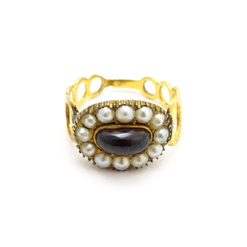 809 - Memorial / Mourning Jewellery: A 19thC gold ring set with central garnet cabochon bordered by seed p... 