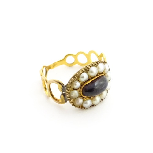 809 - Memorial / Mourning Jewellery: A 19thC gold ring set with central garnet cabochon bordered by seed p... 