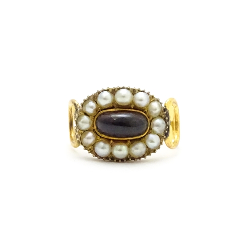 809 - Memorial / Mourning Jewellery: A 19thC gold ring set with central garnet cabochon bordered by seed p... 