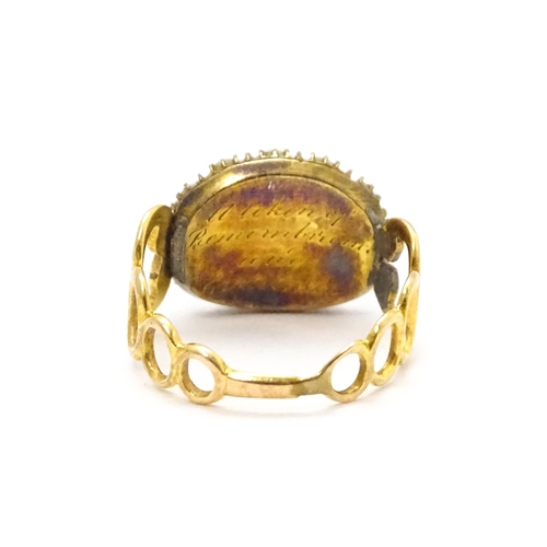 809 - Memorial / Mourning Jewellery: A 19thC gold ring set with central garnet cabochon bordered by seed p... 