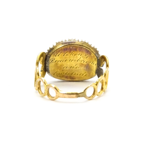 809 - Memorial / Mourning Jewellery: A 19thC gold ring set with central garnet cabochon bordered by seed p... 