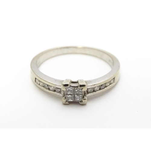 815 - A 9ct white gold ring set with central diamond flanked by further diamonds to shoulders. Ring size a... 