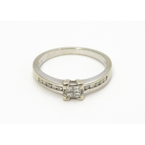 815 - A 9ct white gold ring set with central diamond flanked by further diamonds to shoulders. Ring size a... 