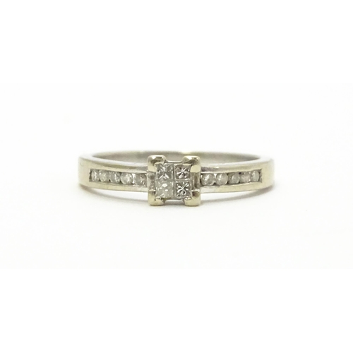 815 - A 9ct white gold ring set with central diamond flanked by further diamonds to shoulders. Ring size a... 