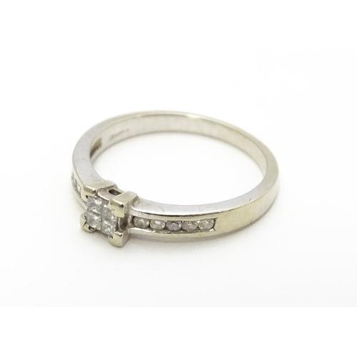 815 - A 9ct white gold ring set with central diamond flanked by further diamonds to shoulders. Ring size a... 