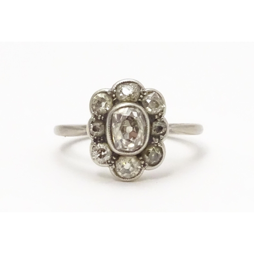 816 - A white gold ring set with central oval diamond, bordered by 8 further diamonds in a floral setting.... 