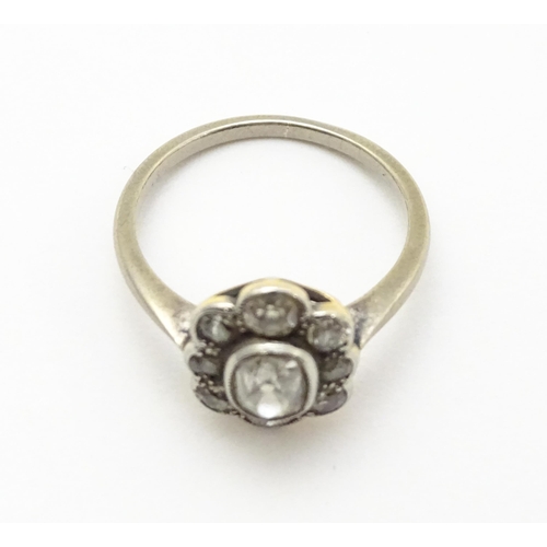 816 - A white gold ring set with central oval diamond, bordered by 8 further diamonds in a floral setting.... 