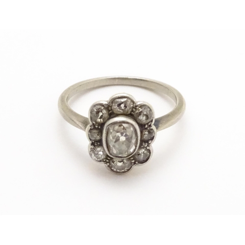 816 - A white gold ring set with central oval diamond, bordered by 8 further diamonds in a floral setting.... 