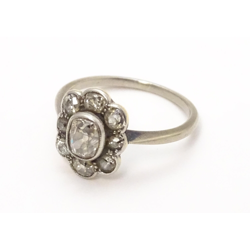 816 - A white gold ring set with central oval diamond, bordered by 8 further diamonds in a floral setting.... 