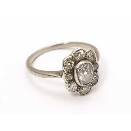 816 - A white gold ring set with central oval diamond, bordered by 8 further diamonds in a floral setting.... 