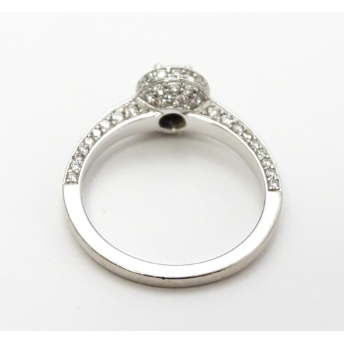 819 - A Bucherer 18ct white gold ring set with central diamond bordered by a profusion of diamonds. With o... 