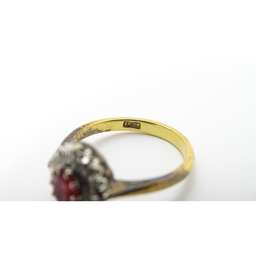 823 - An 18ct gold ring set with central ruby bordered by diamonds. Ring size approx. M